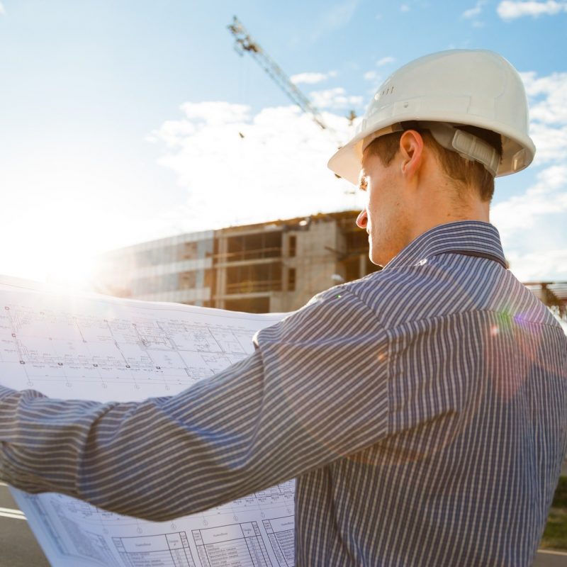 Architect in helmet with blueprints looks at camera in a building site Architect in helmet with blueprints looks at camera in a building site
