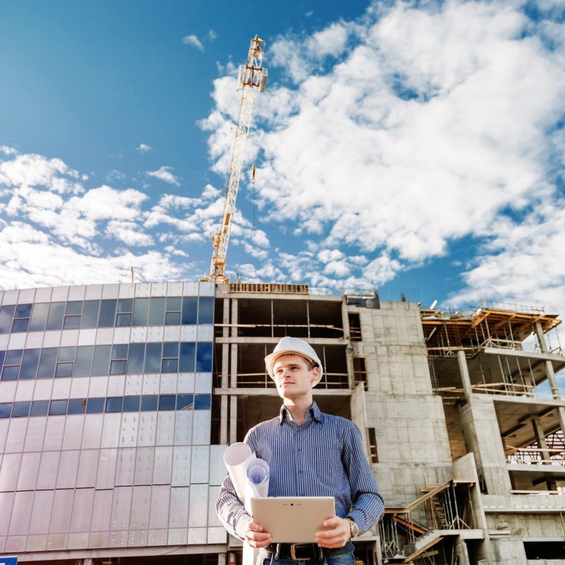 Construction manager controlling building site with plan Construction manager controlling building site with plan